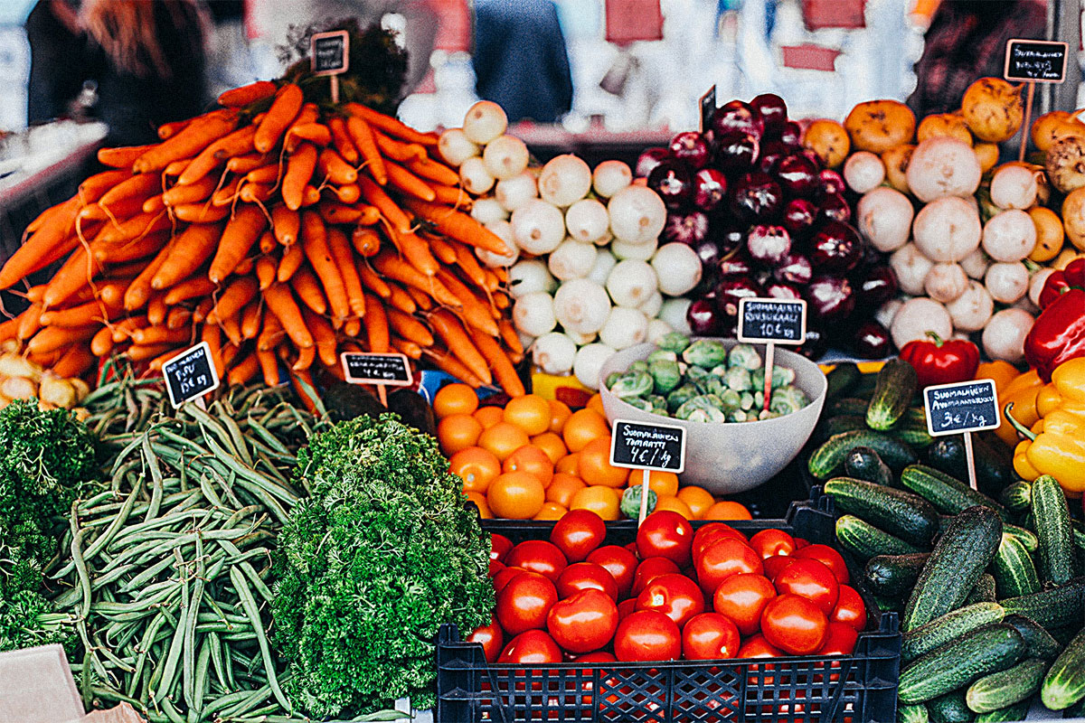 Photo of carrots, onions, tomatoes and parceley at a farmers market.